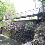 View of pedestrian bridge and water seepage on the downstream face of the dam