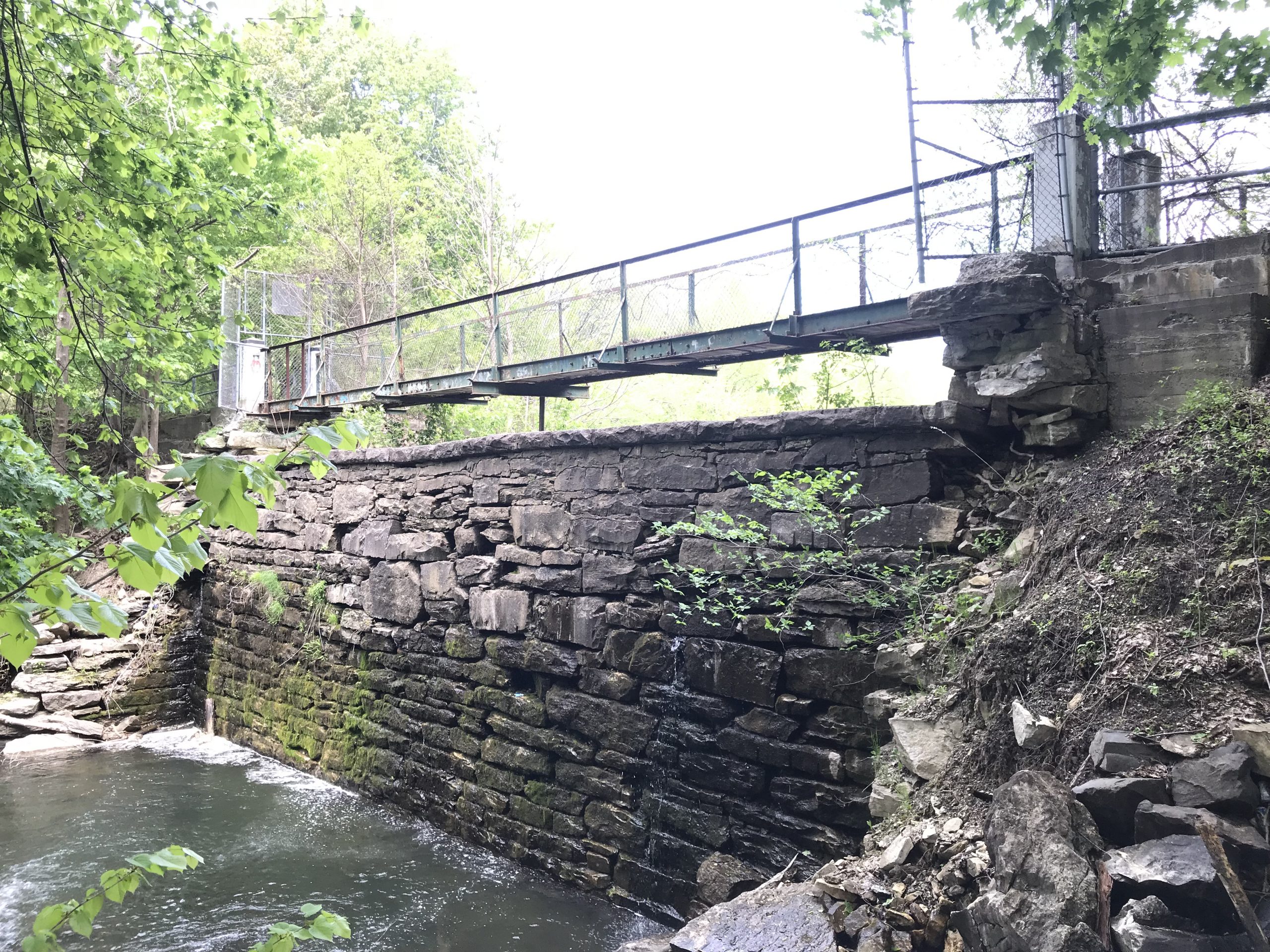 View of pedestrian bridge and water seepage on the downstream face of the dam